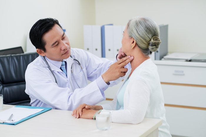Doctor checking thyroid glands of senior woman