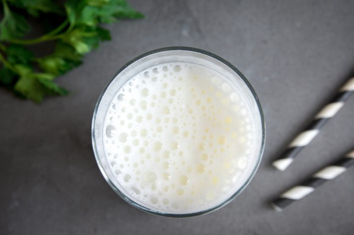 Fresh plain homemade yougurt (yogurt, youghurt, kefir, ayran, lassi) in glass with herbs over gray background, copy space. Probiotic cold fermented dairy drink.