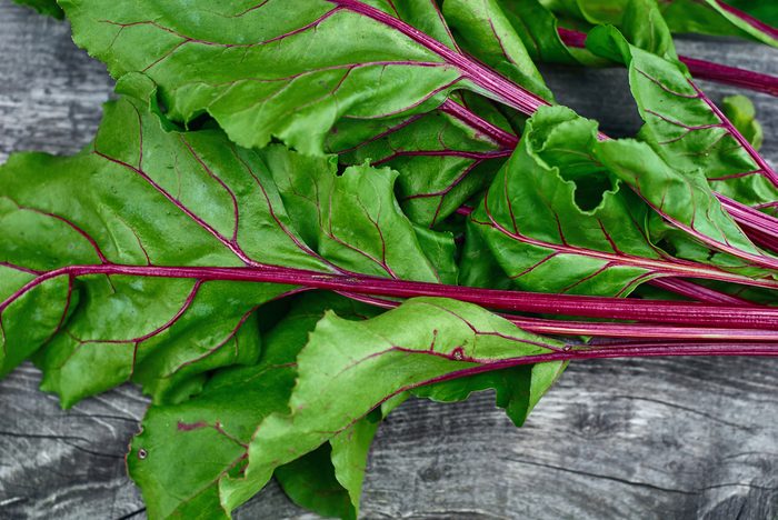 Wooden vintage background for design with fragment bright green, beautiful beet haulm. Top view