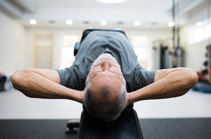 Fit senior man in gym working his abs, doing crunches.