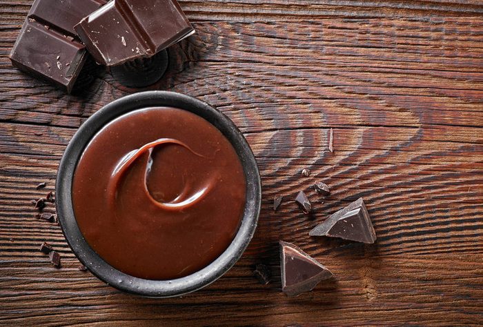Chocolate cream and chocolate pieces on wooden table