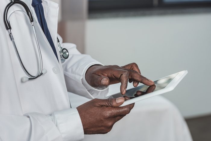 Cropped image of african american doctor searching something on a tablet