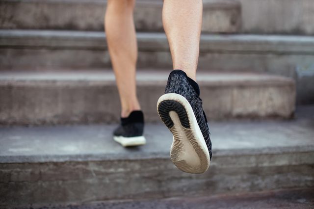 Close up of male feet in sneakers walking up the stairs. Athlete man legs running up