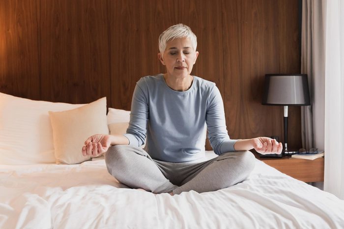 senior woman meditating on bed