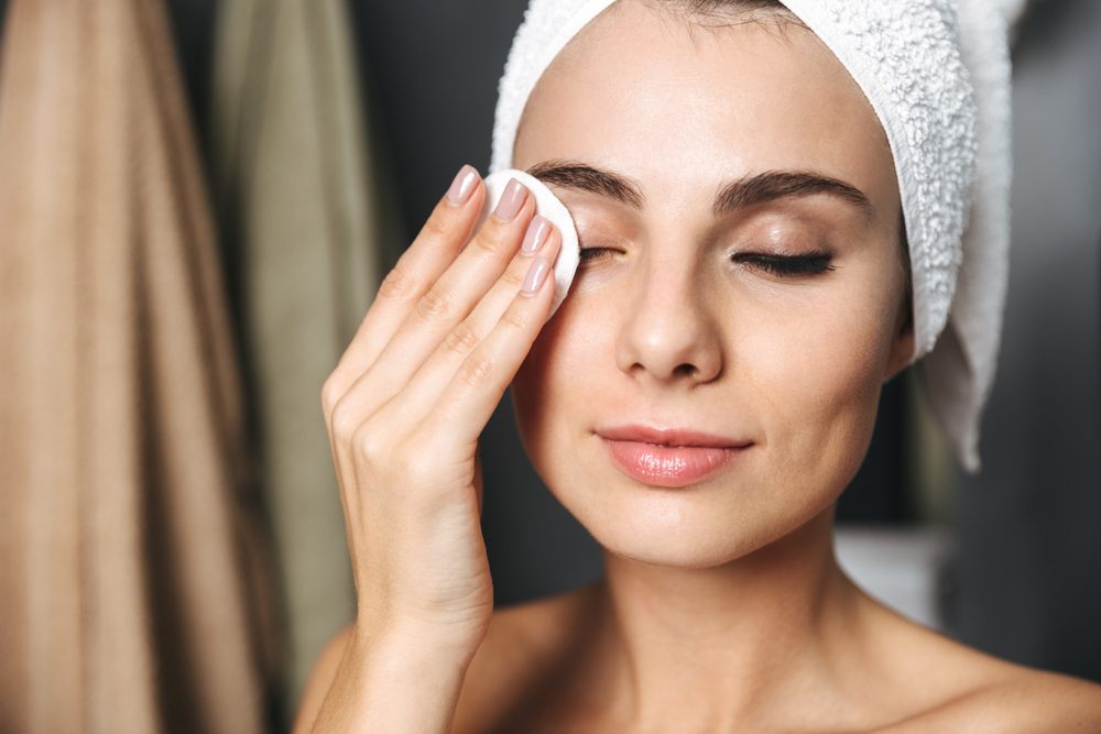 woman removing eye makeup with a cotton pad