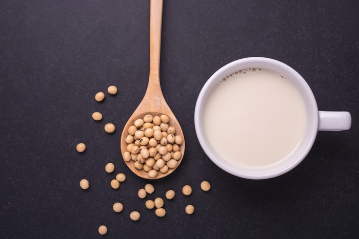 Soy milk in white cup and soy bean on dark table background. Top view
