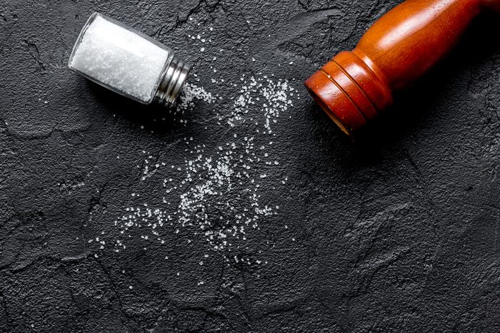 salt and saltcellar on black stone table background top view mock-up