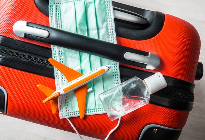 mask and hand sanitizer on suitcase travel concept during covid-19