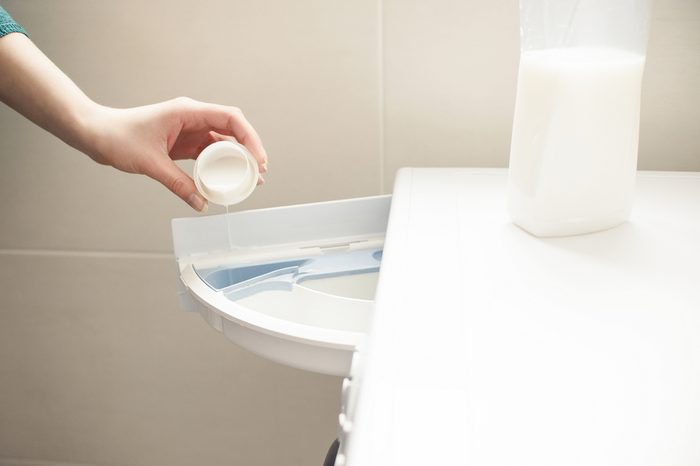 Woman fills the washing machine with fabric softener.
