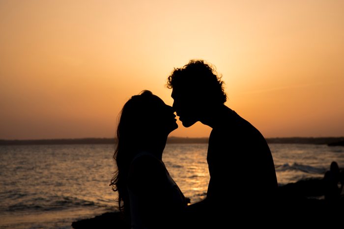 man and woman kissing silhouette during sunset