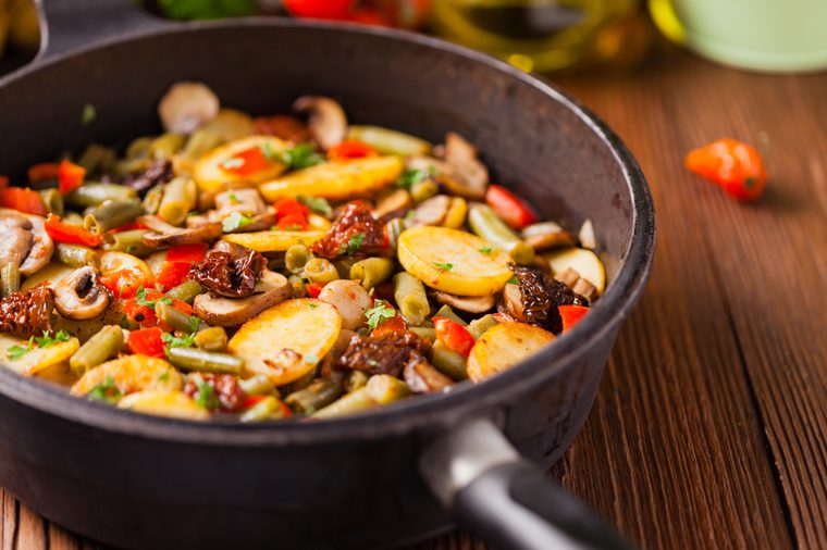 Fried pan vegetables, with mushrooms and dried tomatoes. Seasoned with a mix of herbs.Top view.