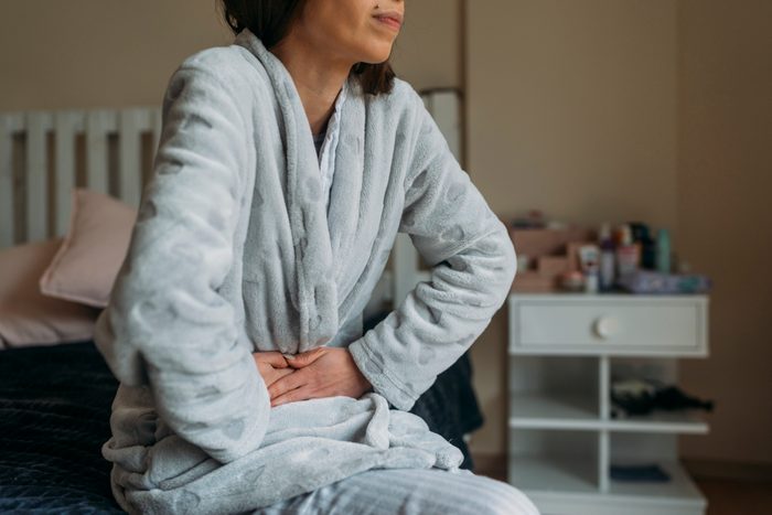 woman sitting on bed with Abdominal pain