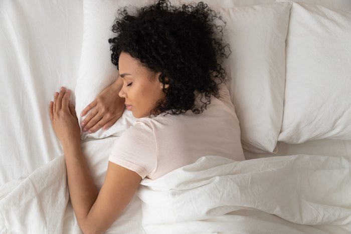 Healthy serene girl sleeping in comfortable bed, top view
