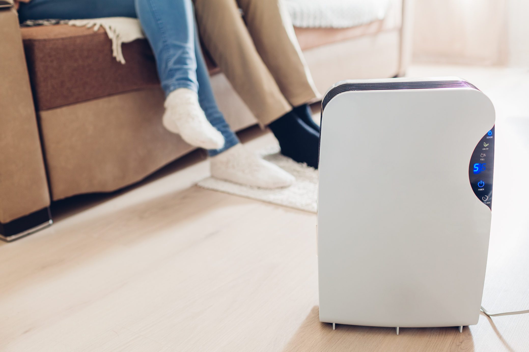 Dehumidifier with touch panel, humidity indicator, uv lamp, air ionizer, water container works in apartment. Close up