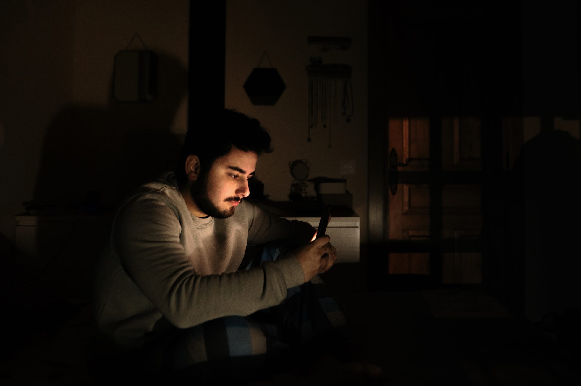 Young man in bed looking at his smartphone screen