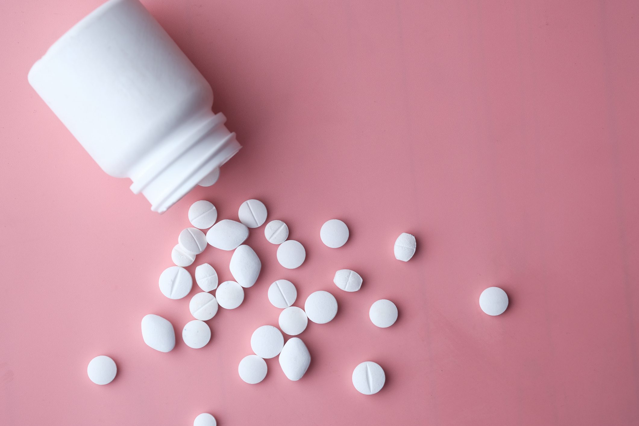 White Pills Spilling From Bottle On Pink