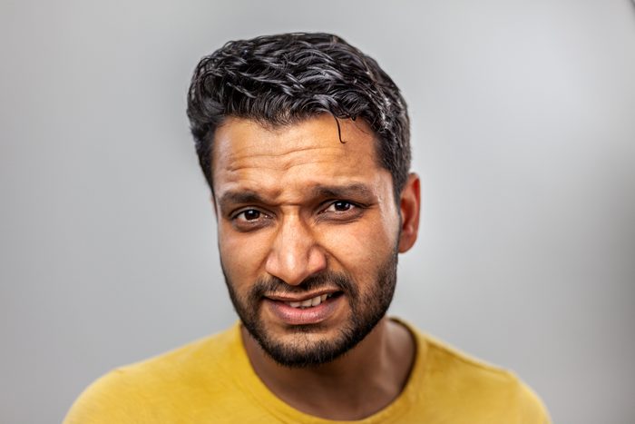 Young man making disgusted face after experiencing metal mouth