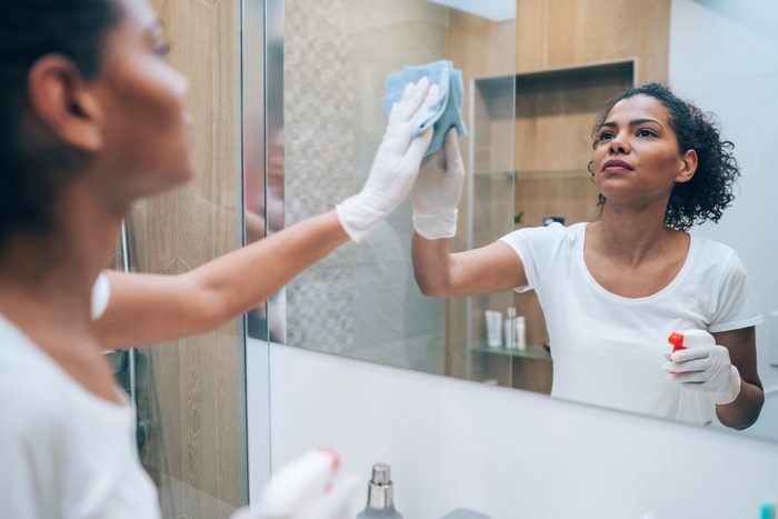 woman cleaning and disinfecting bathroom