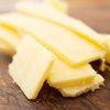 Slices of cheddar cheese on a worn rustic chopping board.