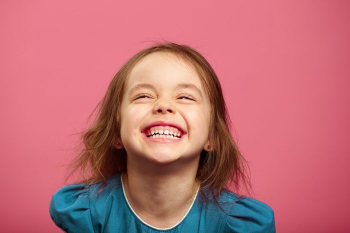 Joyful little girl sincere laughing at pink isolated background.