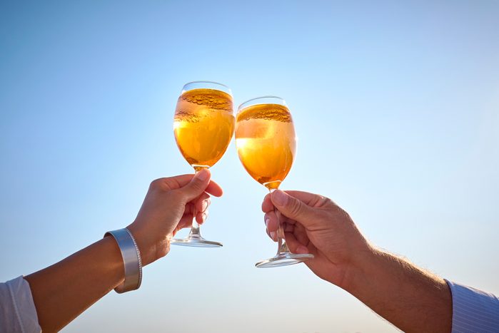 Couple clinking spritz glasses before blue sky