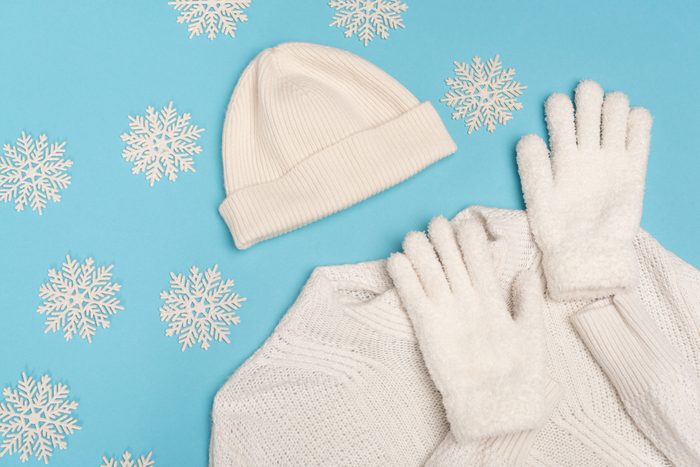 top view of winter white knitwear and snowflakes on blue background