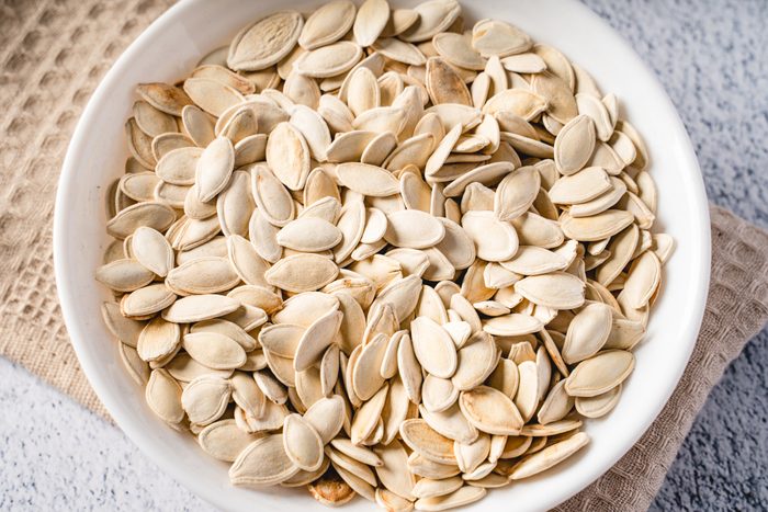 Top view on fresh salted roasted pumpkin seeds in bowl on table