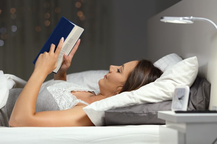 Woman reading a book in the night on the bed