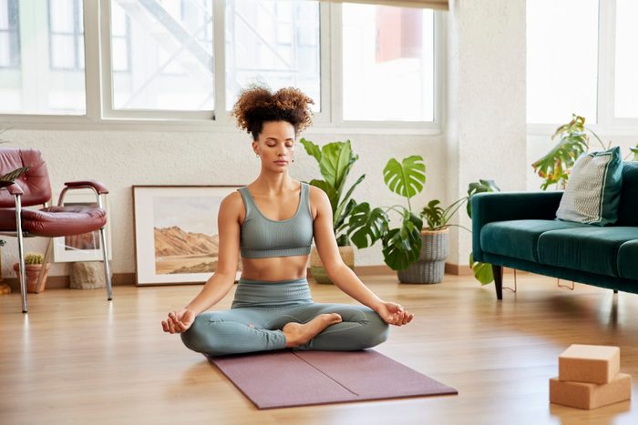 Young Woman Meditating In Living Room