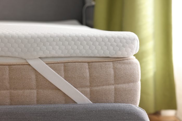 White memory foam mattress topper on grey bed, closeup