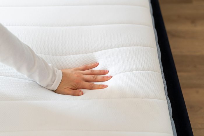 Cropped shot of woman hand testing new orthopedic memory foam core mattress