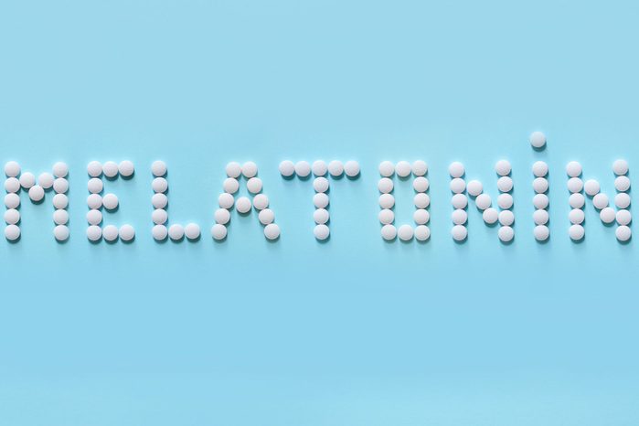 Melatonin, the word is laid out on a blue background of tablets. Tablets, hormone and excipients to improve sleep.