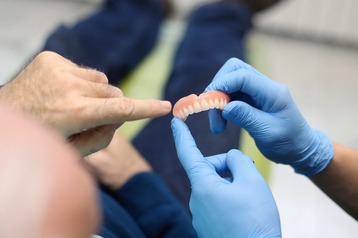 man looking at dentures in dentist's office