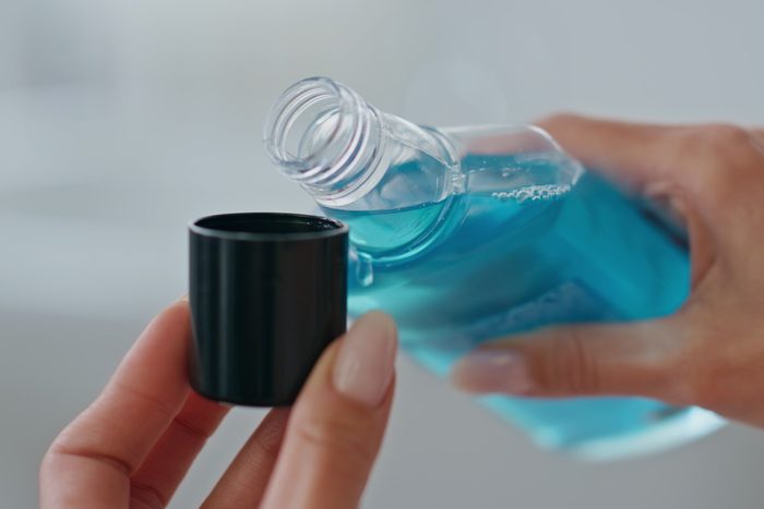 person during antibacterial mouth rinse into bottle cap