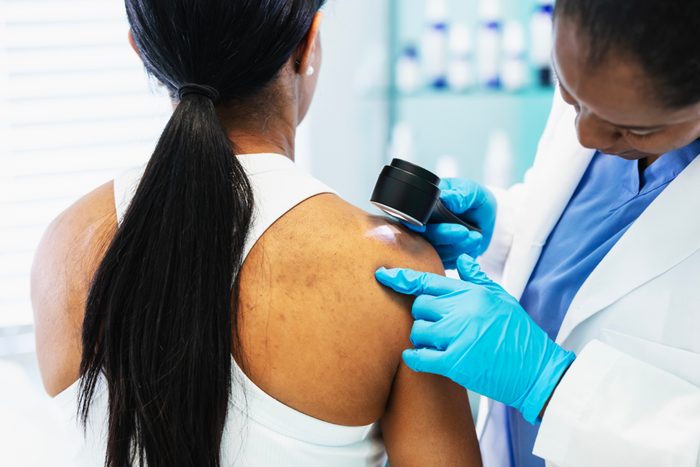 Female dermatologist screening patient for skin cancer