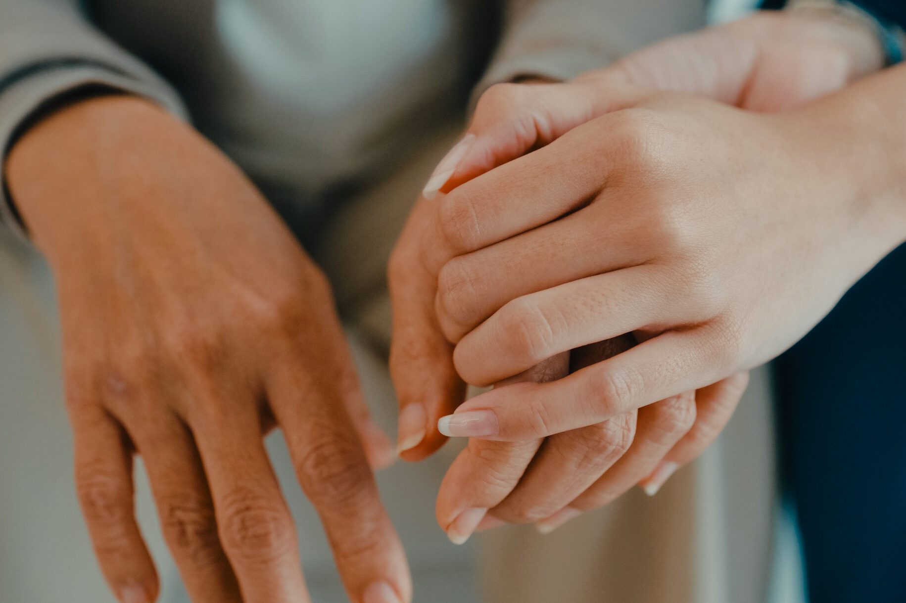 Close-up of Young Asian nurse comforts an elderly woman on a sofa, emotional support and care in living room at home. Home health care.
