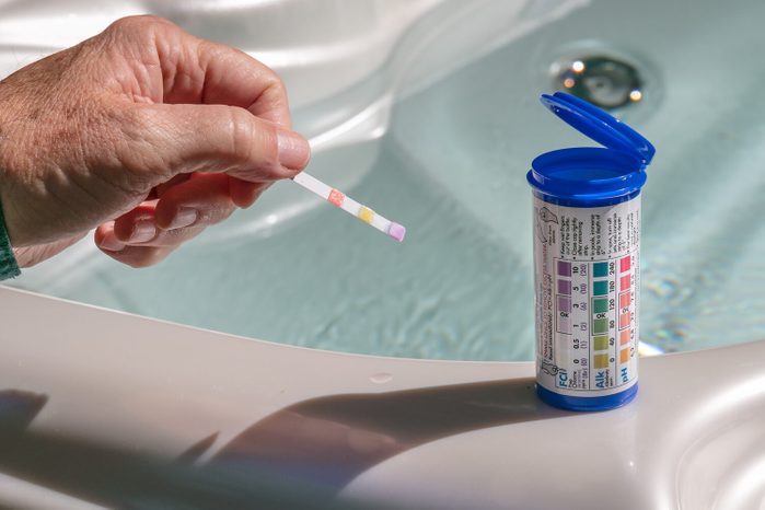 Hand with pH test strip for water chemistry