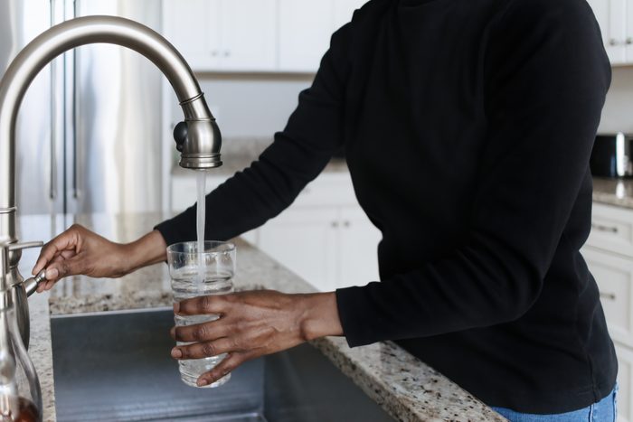 Woman Fills Glass With Water From Kitchen Sink