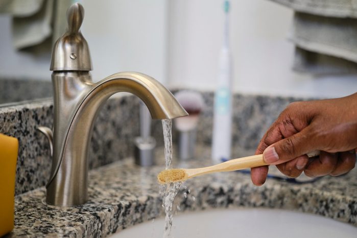 Toothbrush Rinsing Under Water at a Bathroom Faucet