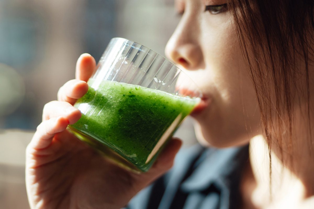 woman drinking celery juice from glass